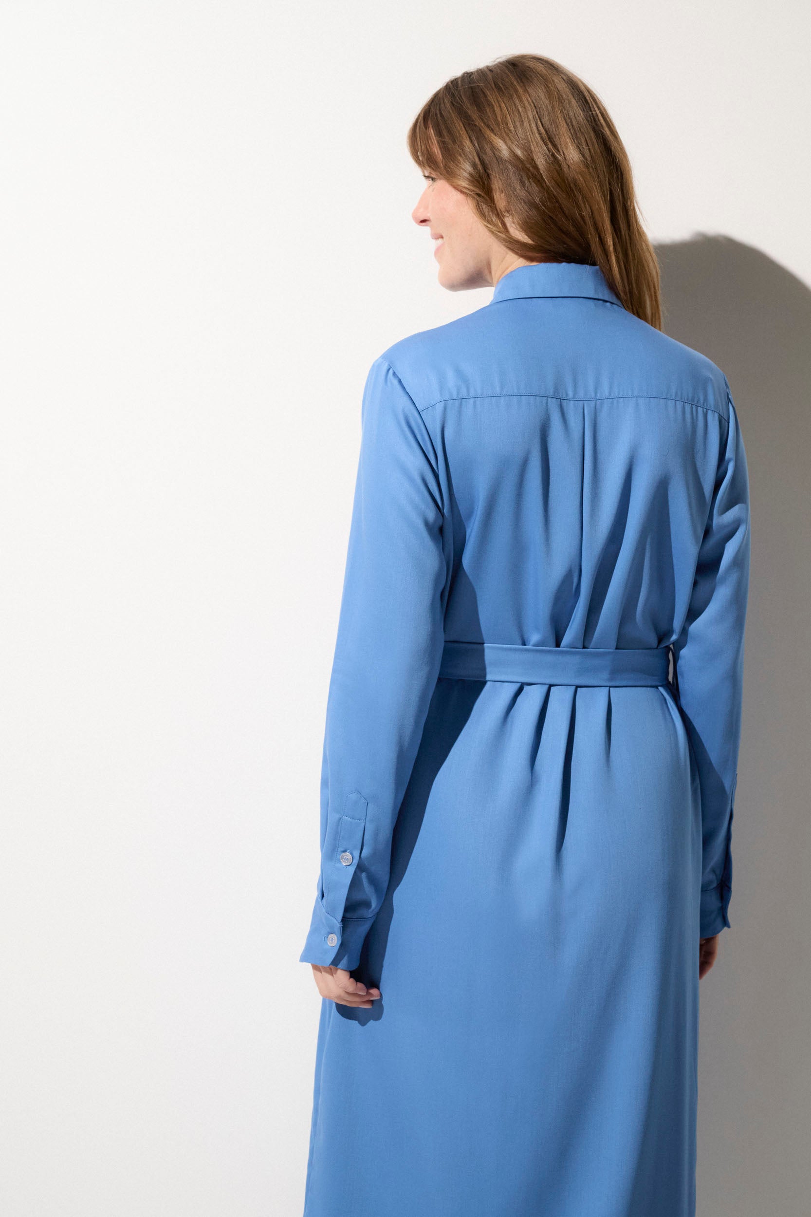 Femme portant une robe chemise anti-UV bleu, élégante et légère, offrant protection solaire UPF 50+.