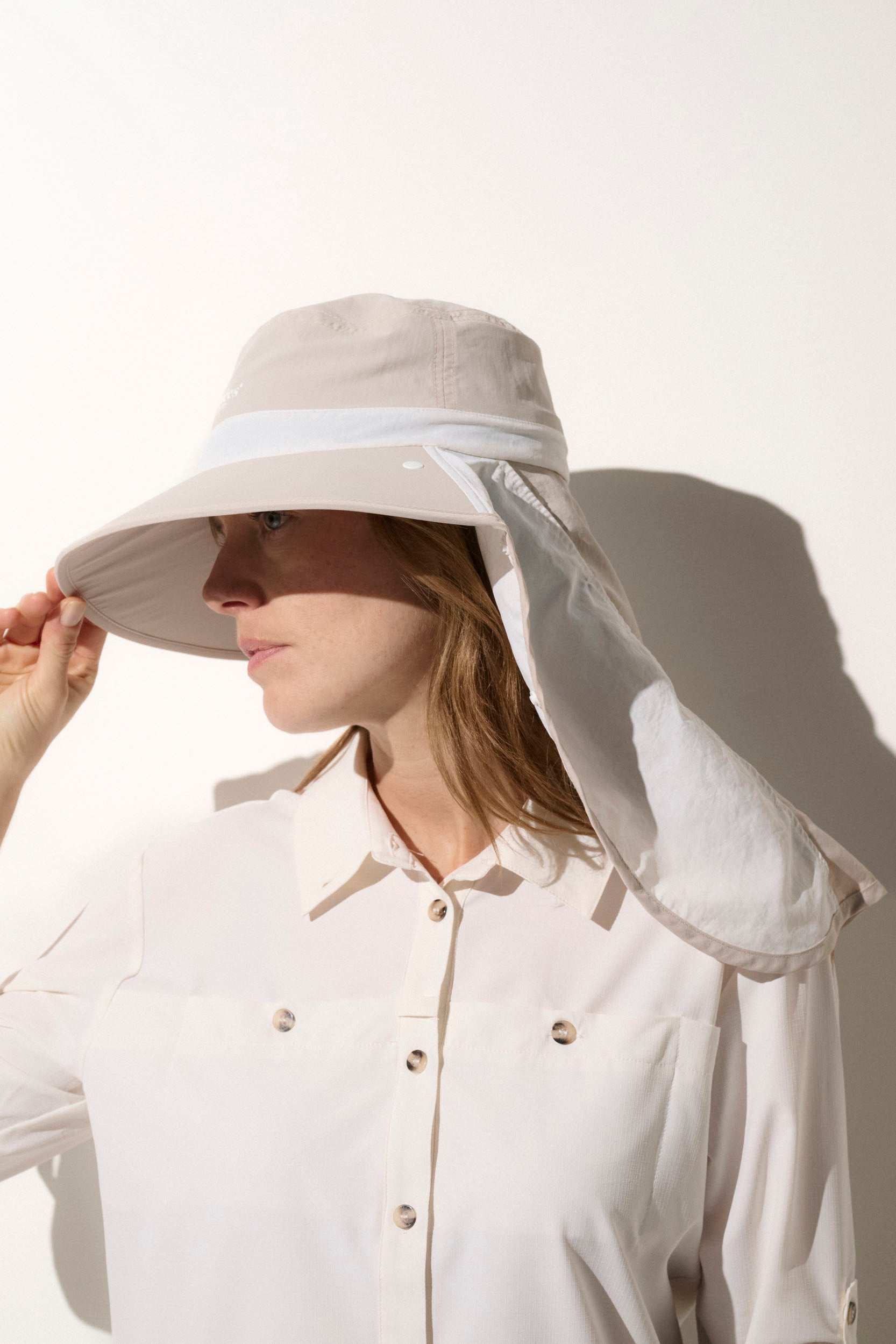 Chapeau anti-UV blanc UPF50+ pour femme, offrant une protection solaire lors d'activités en extérieur.