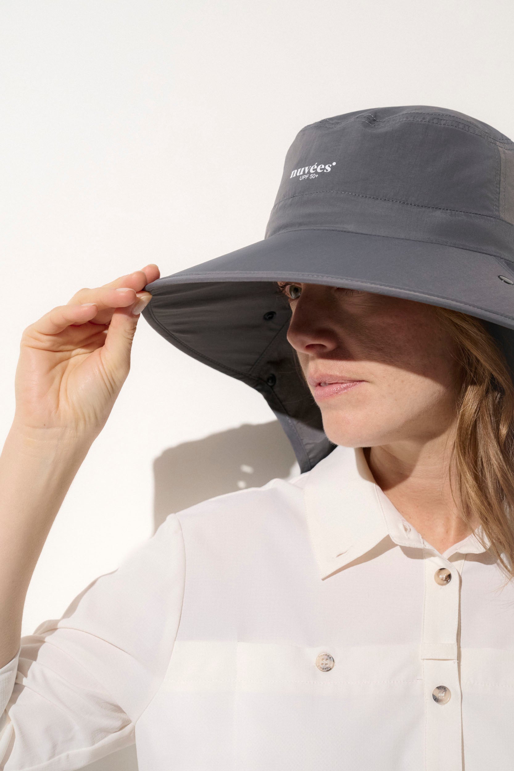 Chapeau anti-UV gris UPF50+ porté par une femme, idéal pour une protection solaire lors des activités en plein air.