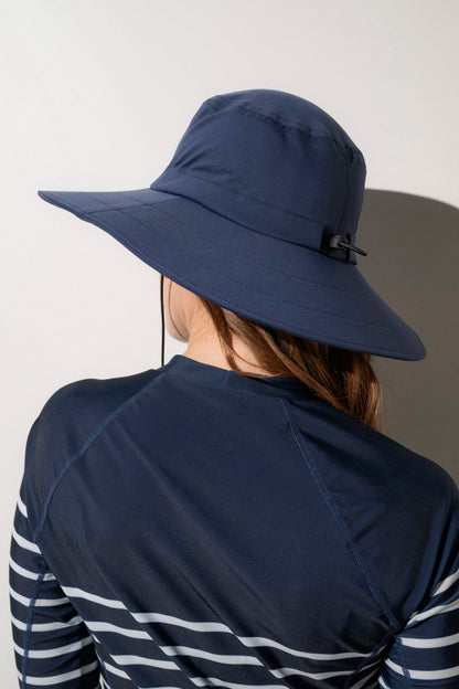 Chapeau de bain anti-UV bleu marine UPF50+ porté par une femme, idéal pour les activités sous le soleil.