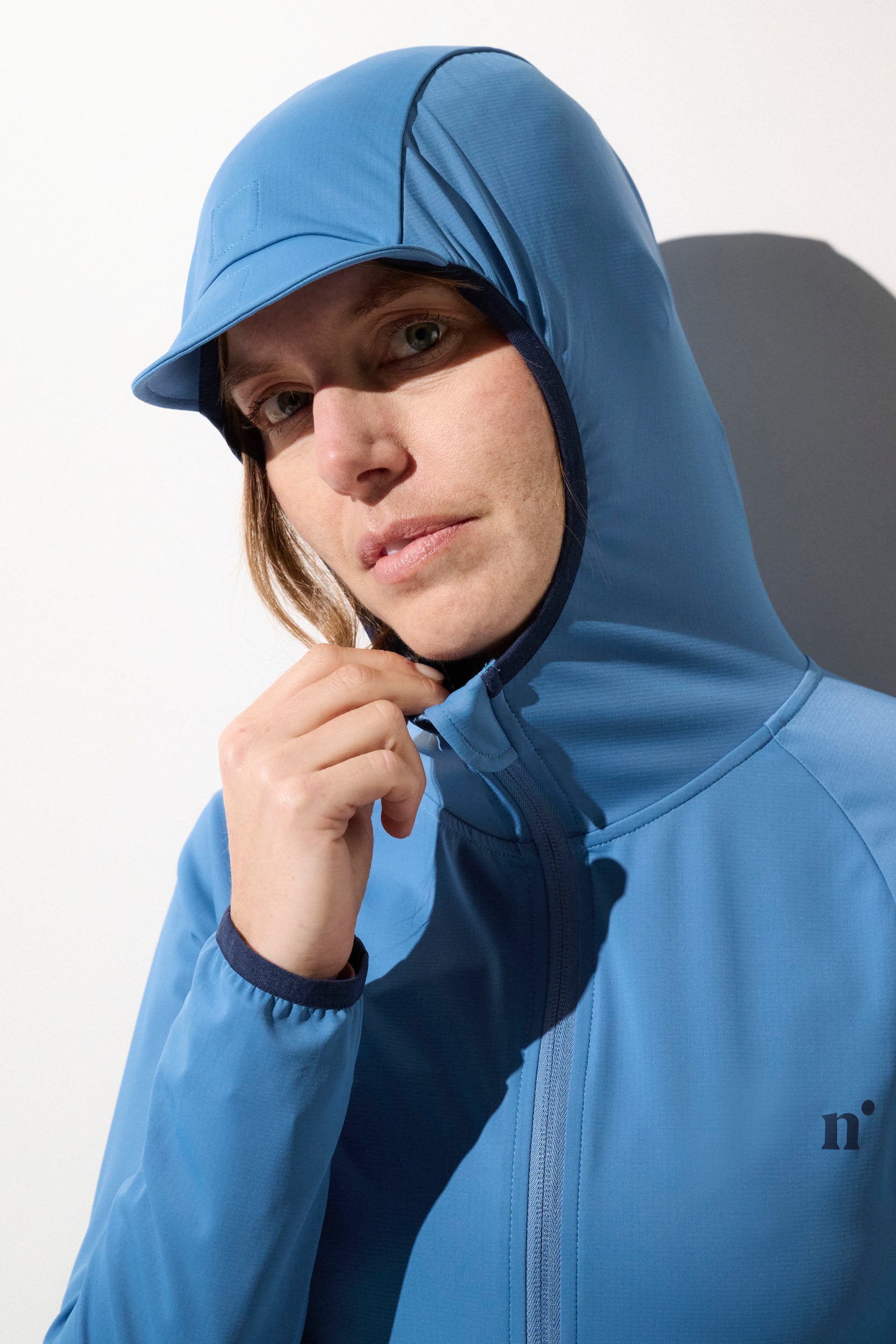 Veste anti-UV bleue pour femme, avec capuche, tissu léger et UPF 50+, idéale pour les activités en extérieur.