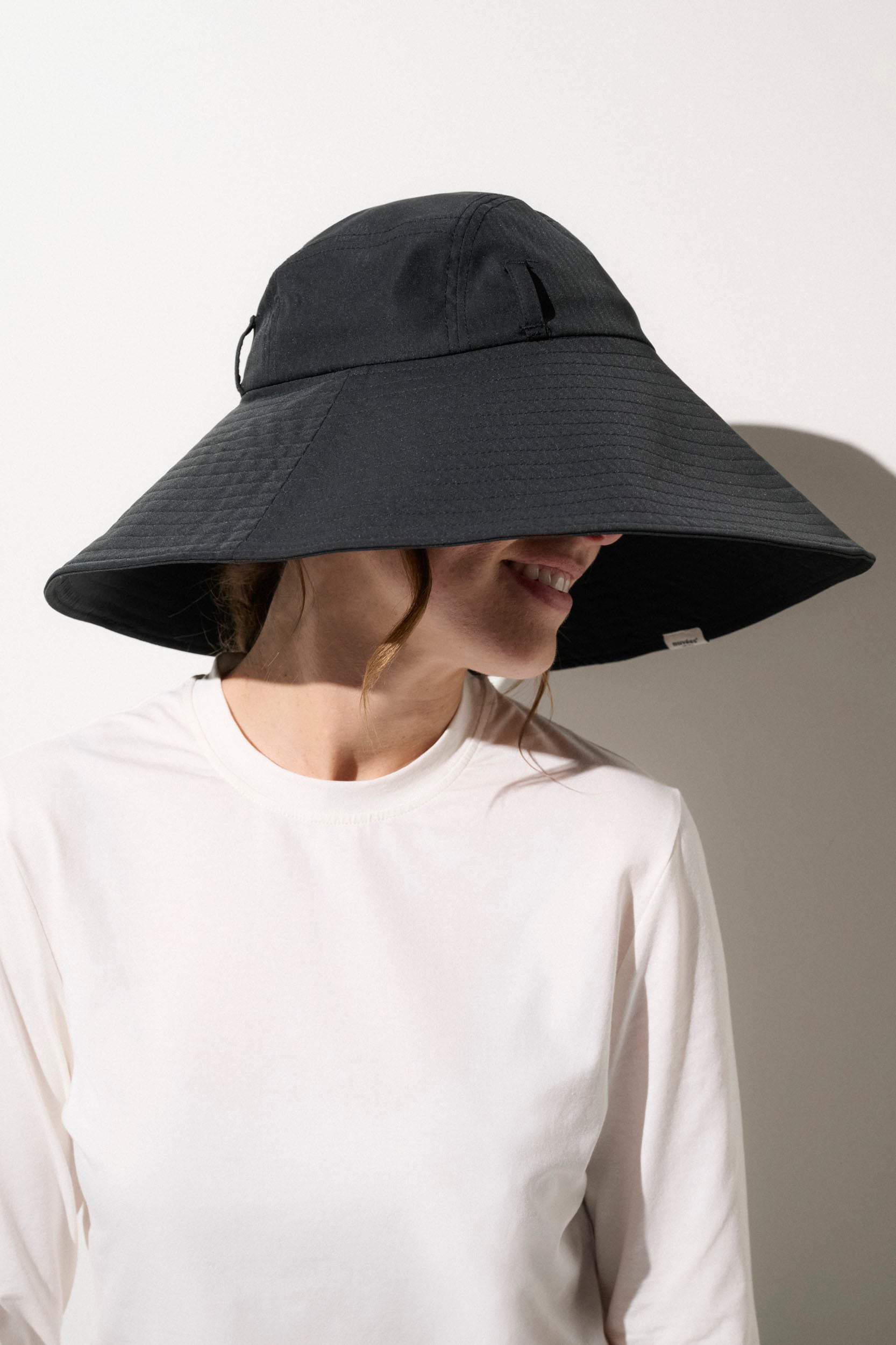 Chapeau anti-UV noir UPF50+ porté par une femme, idéal pour la protection solaire lors des activités extérieures.