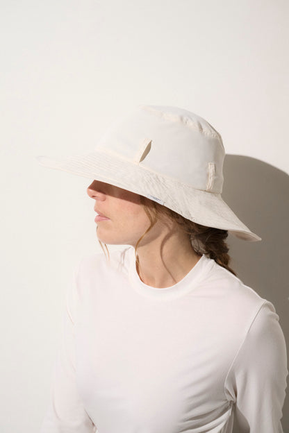 Chapeau anti-UV blanc UPF 50+ porté par une femme, léger et élégant pour une protection solaire quotidienne.