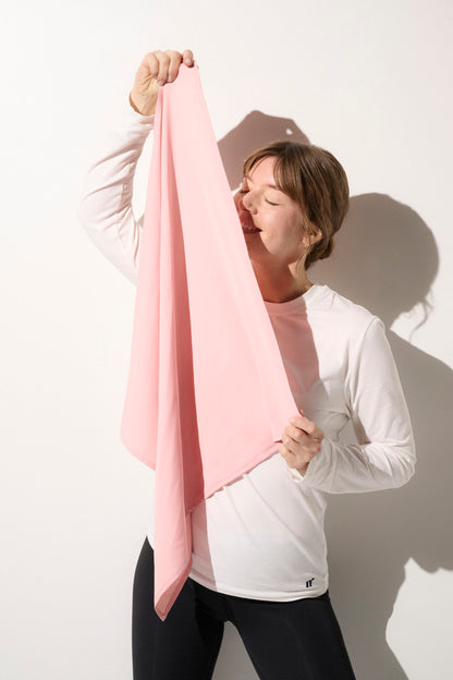 Femme souriante portant un foulard anti-UV rose, UPF50+, avec un t-shirt à manches longues pour une protection solaire élégante.