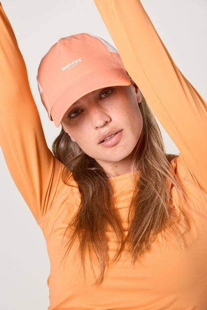 Casquette anti-UV bicolore Sorbet Abricot portée par une femme en vêtement léger, idéale pour le soleil.