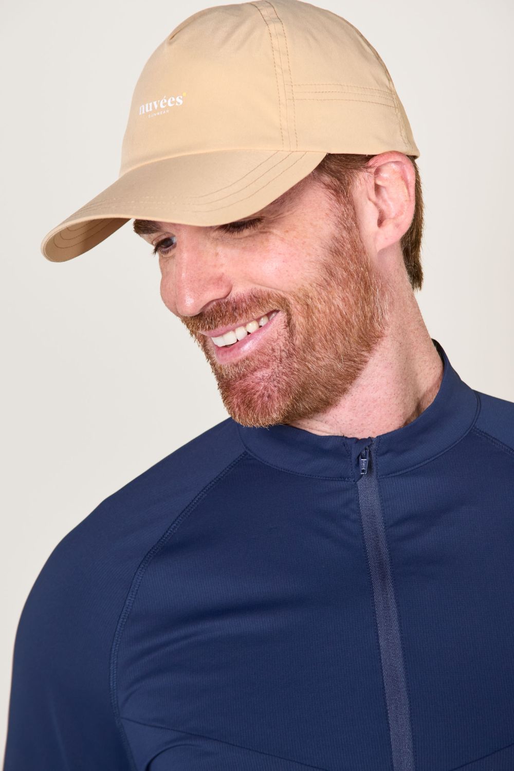 Casquette anti-UV beige portée par un homme souriant, idéale pour les activités de plein air.