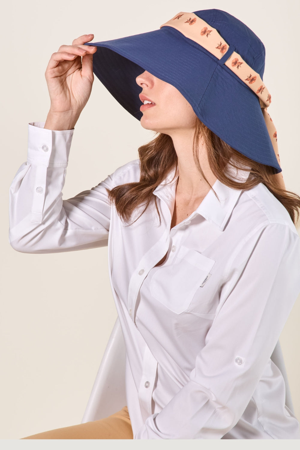 Femme portant un chapeau anti-UV bleu avec large bord pour une protection solaire élégante.