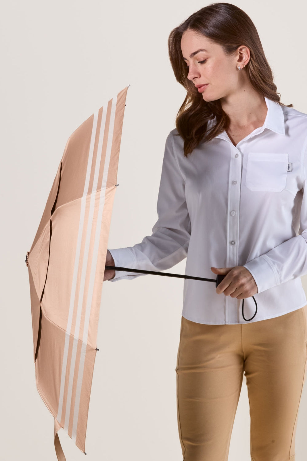 Ombrelle anti-UV beige UPF50+ tenue par une femme, idéale pour une protection solaire lors de promenades.