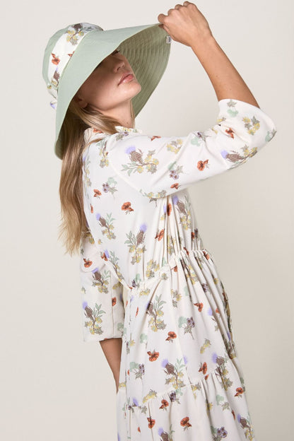 Robe longue anti-UV à manches longues pour femme avec motif fleuri, portant un chapeau, parfait pour la protection solaire UPF 50+.