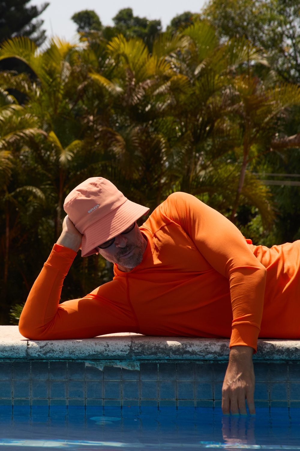 T-shirt de bain anti-UV orange à manches longues, homme décontracté près d'une piscine, protection solaire UPF 50+.